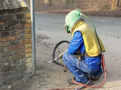 Ein Mitarbeiter führt Sandstrahlen durch